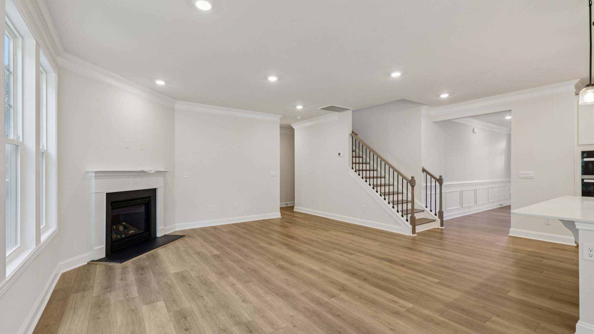 Living room space beside kitchen with wood floors and fireplace