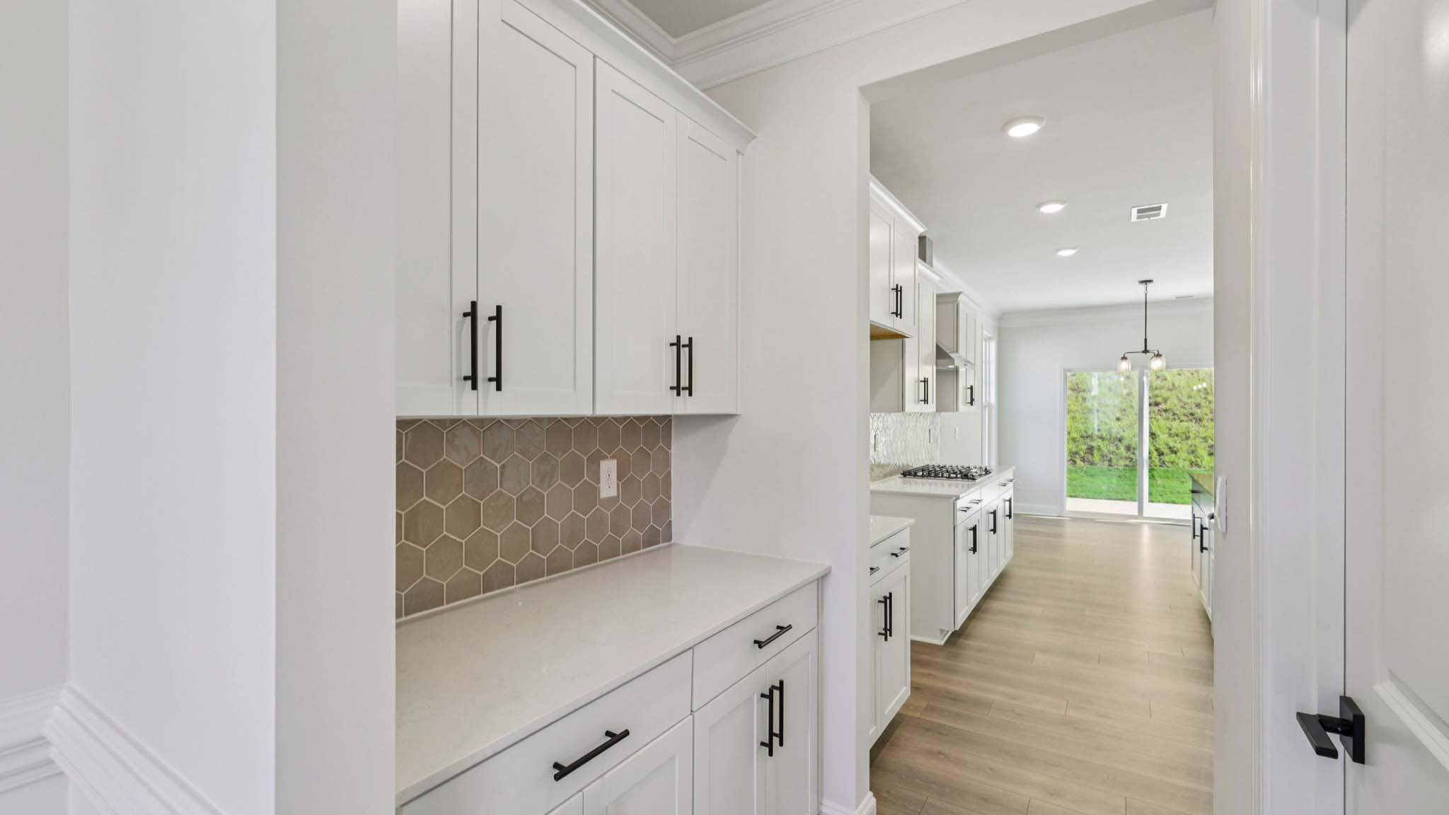 Kitchen and island with white cabinets and counters, wood floors, and stainless steel appliances