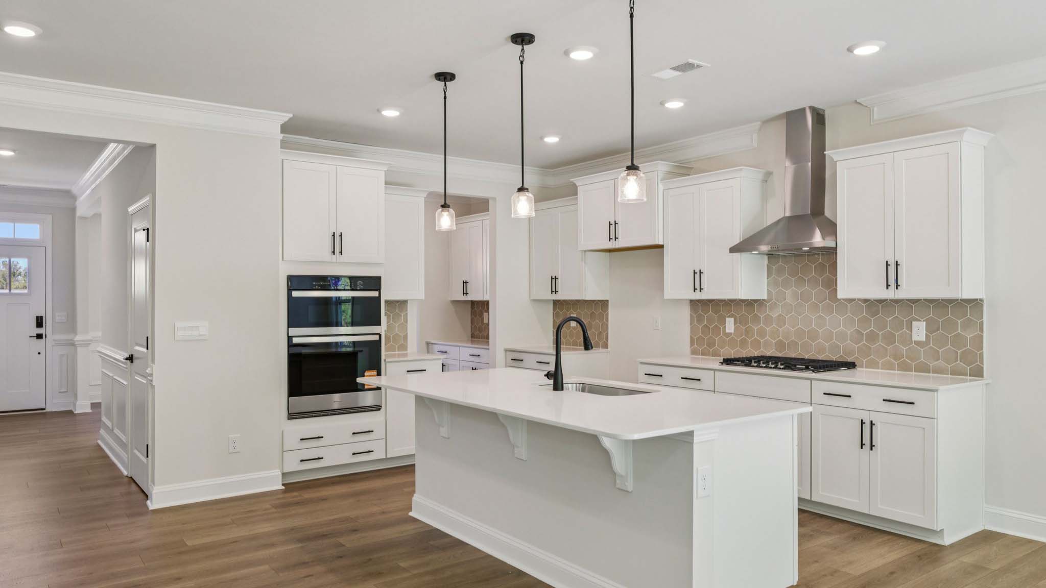 Kitchen and island with white cabinets and counters, wood floors, and stainless steel appliances