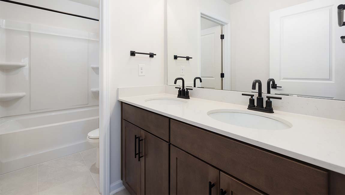 Bathroom with double sinks, white cabinets and counters