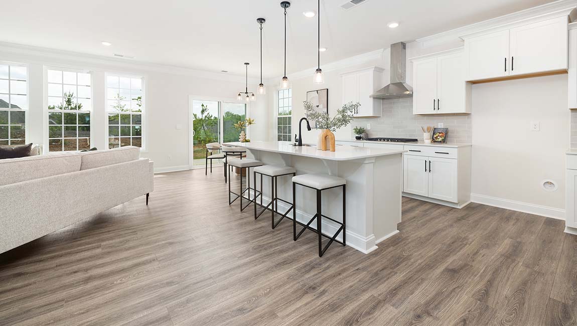 Kitchen and island with white cabinets and counters, wood floors, and stainless steel appliances