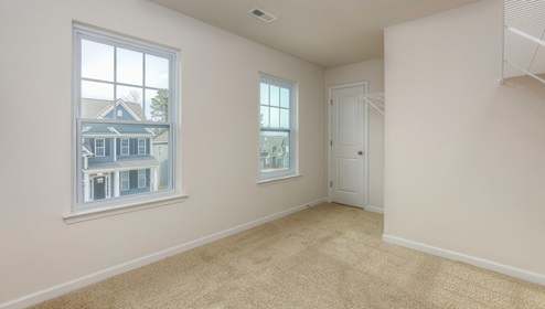 carpeted primary suite with windows walk in closet with windows