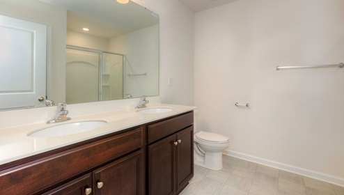 primary suite bathroom with brown cabinets