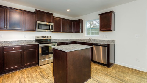 kitchen and island with brown cabinets, and stainless steel appliances