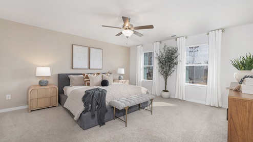 Primary bedroom with carpet, large windows and ceiling fan. new homes in charlotte, nc