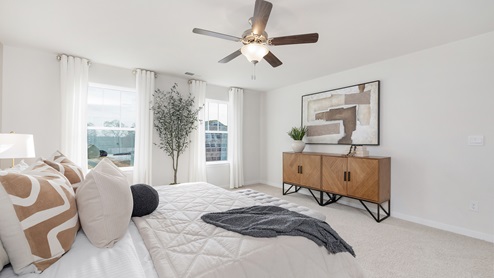 Primary bedroom with carpet, large windows and ceiling fan. new homes in charlotte, nc