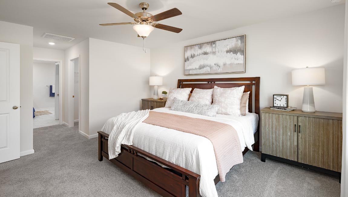Carpeted primary bedroom with large window and ceiling fan. New Home in Charlotte, North Carolina