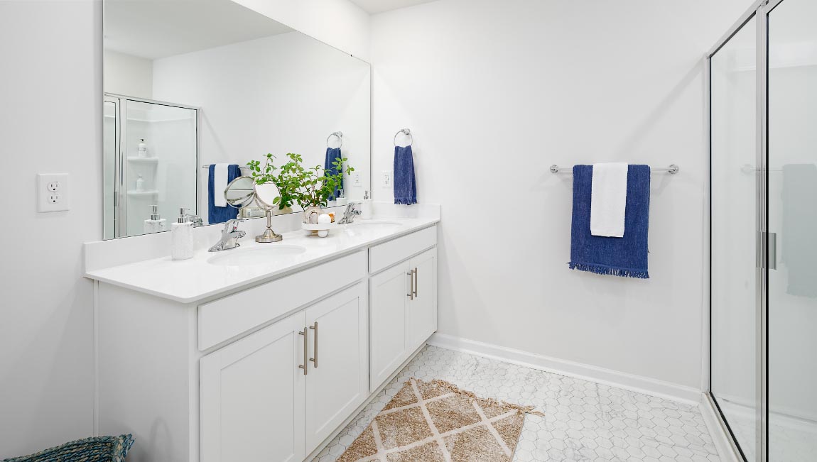Bathroom with white cabinets and counters, double vanity, and glass door shower. New Home in Charlotte, North Carolina