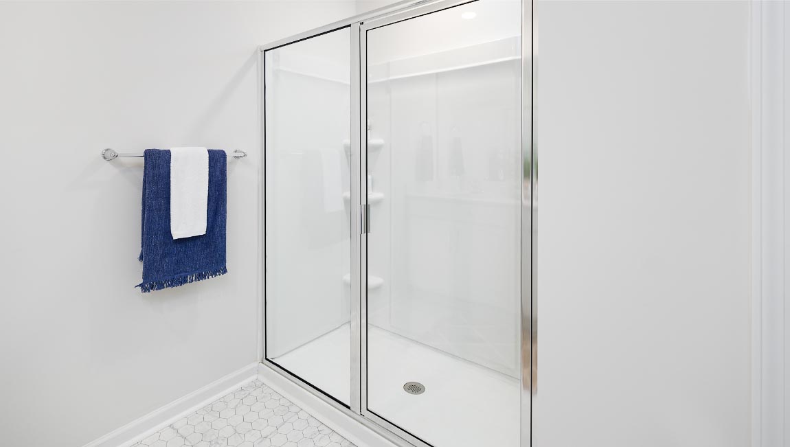 Bathroom with white cabinets and counters, double vanity, and glass door shower. New Home in Charlotte, North Carolina