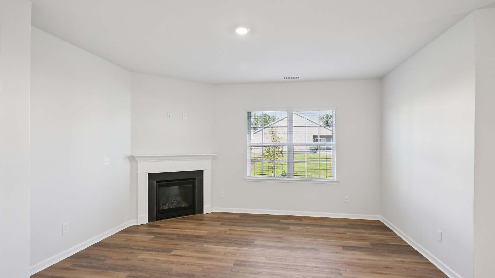 Open living room with wood floors, large window, and fireplace