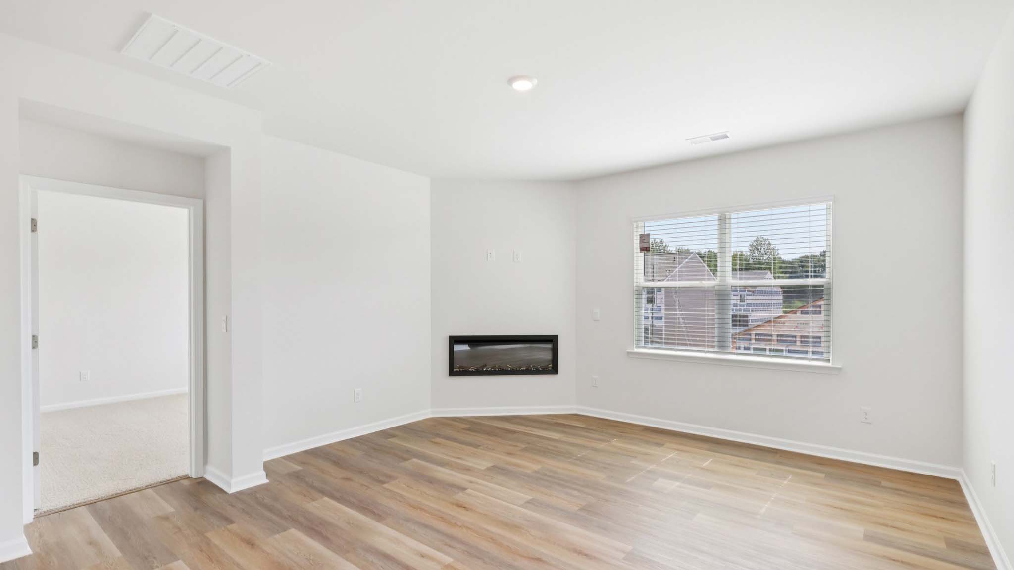 Open living room with wood floors, large window, and fireplace