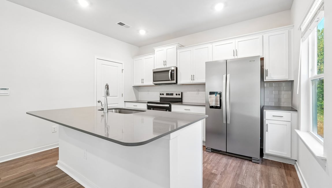 Kitchen and island with white cabinets and wood flooring