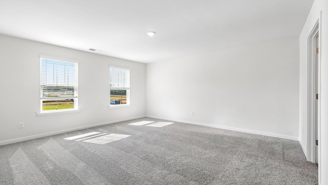 Primary carpeted bedroom with windows