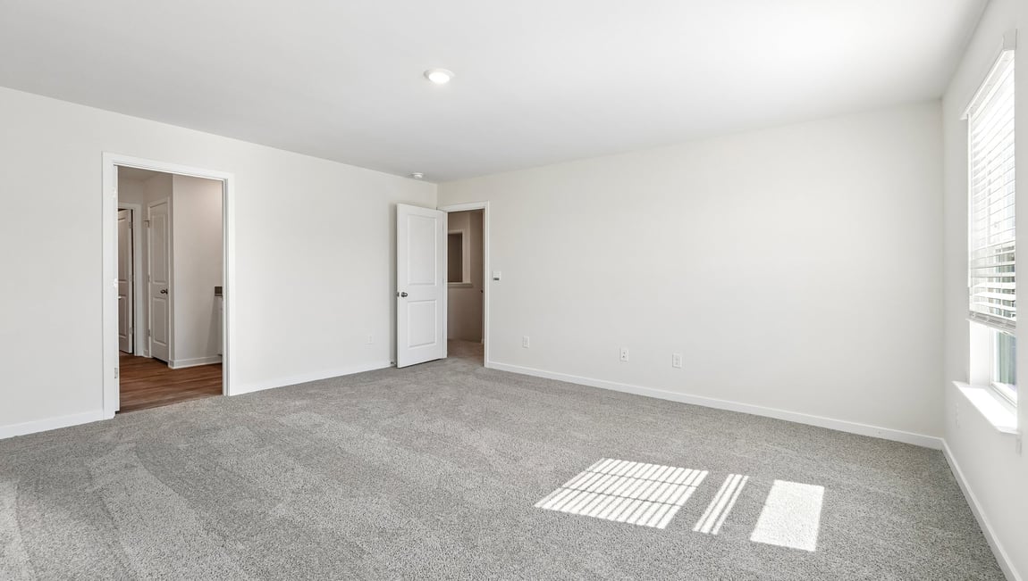 Primary carpeted bedroom with windows