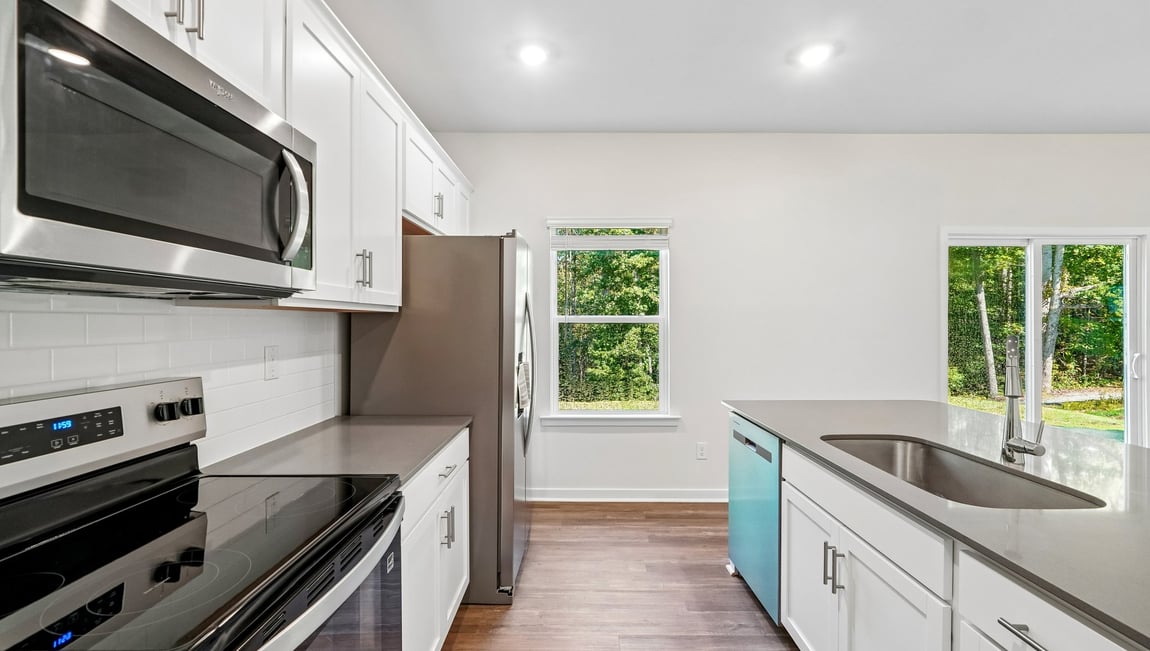 Kitchen and island with white cabinets and wood flooring