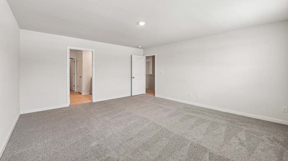Primary carpeted bedroom with windows