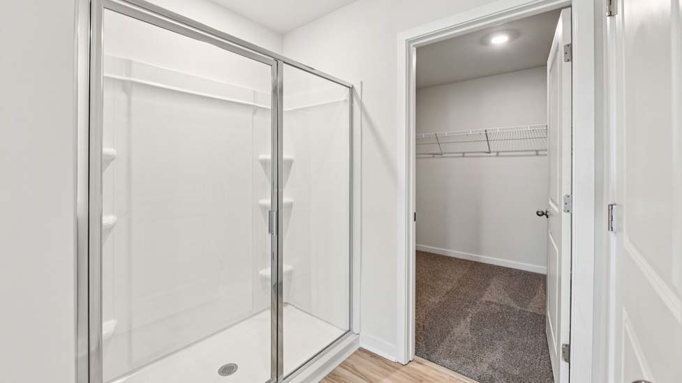 Primary bathroom with standing glass shower and view of closet