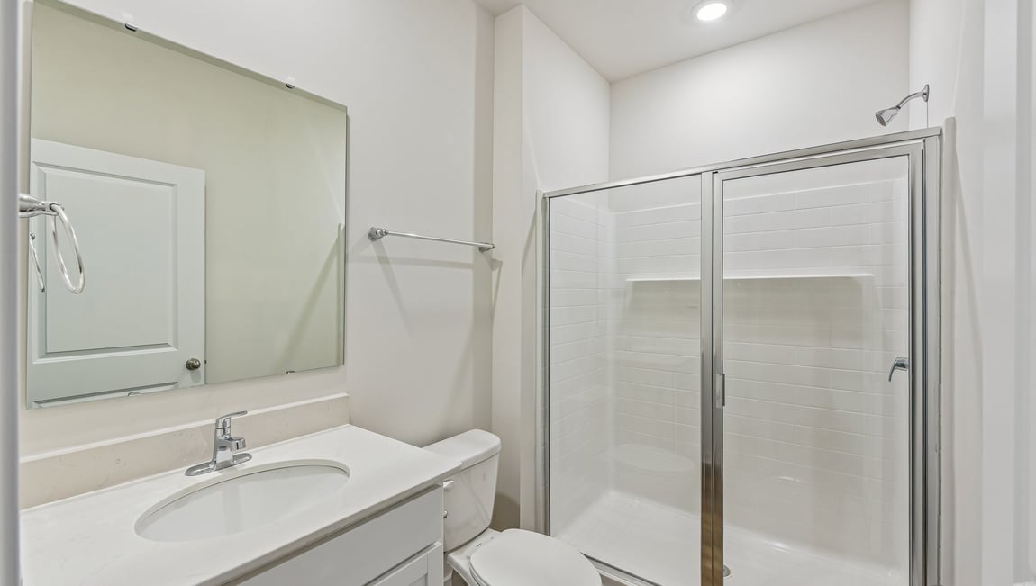Bathroom with standing shower, white counter and cabinets