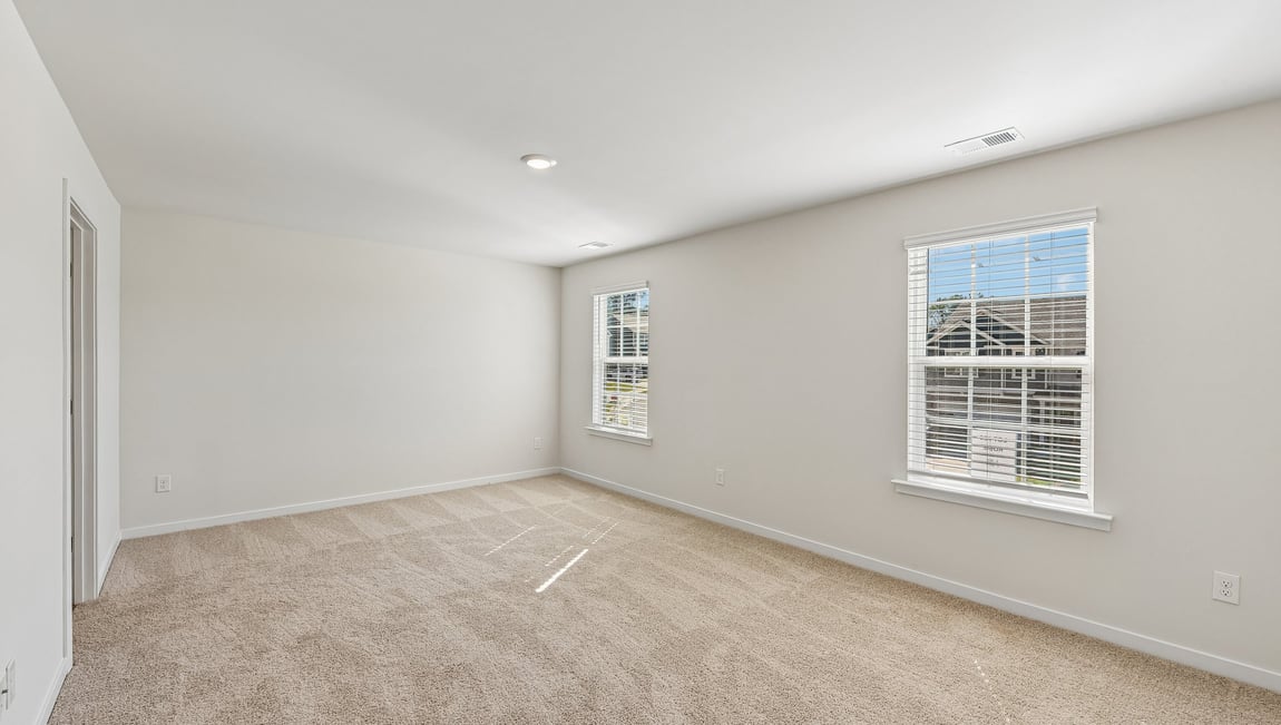 Primary bedroom, carpeted with two large windows