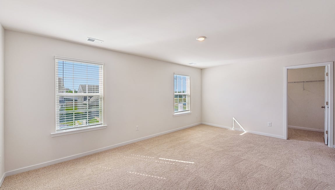 Primary bedroom, carpeted with two large windows