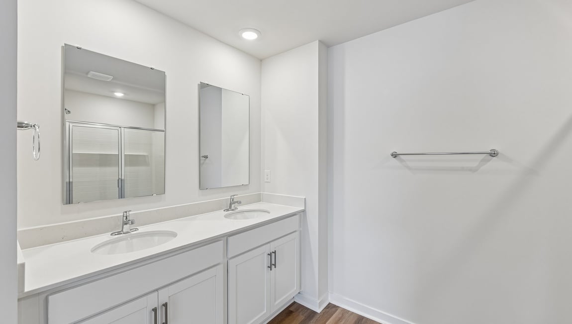 Primary bathroom with double sinks, white cabinets and counters