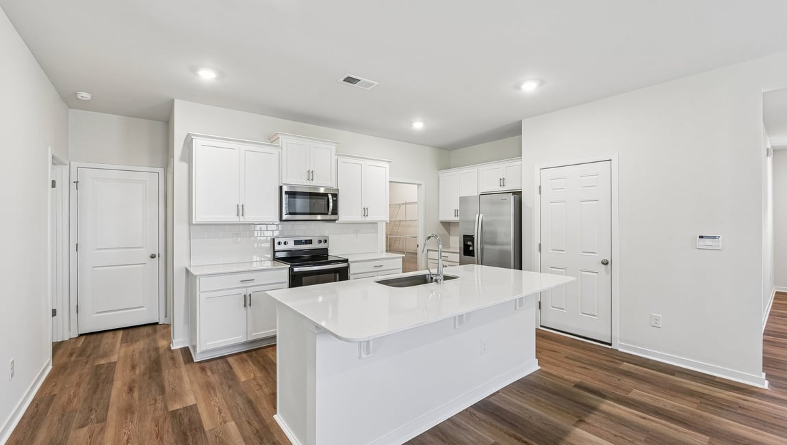 Kitchen and island with white cabinets and wood flooring