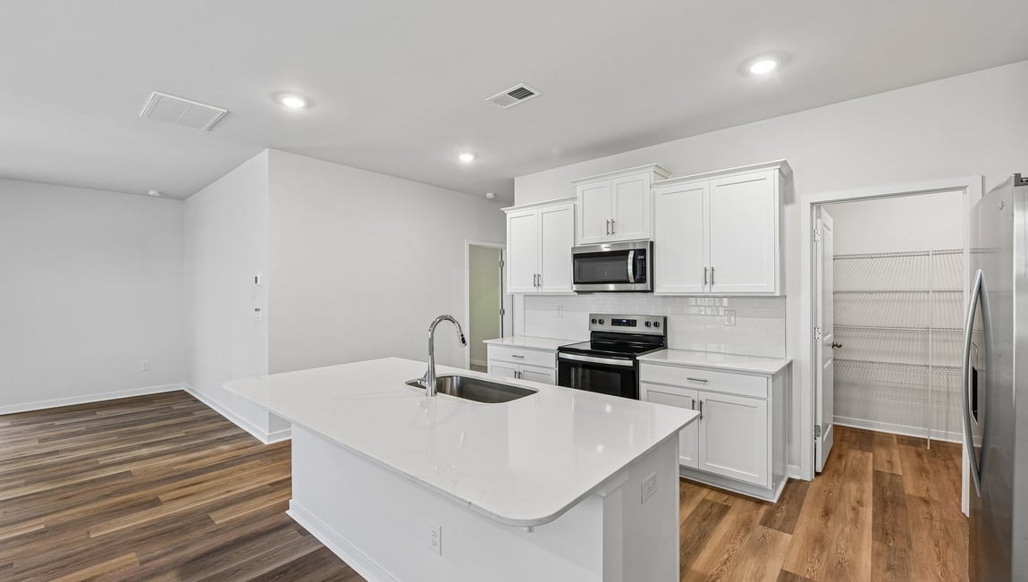 Kitchen and island with white cabinets and wood flooring