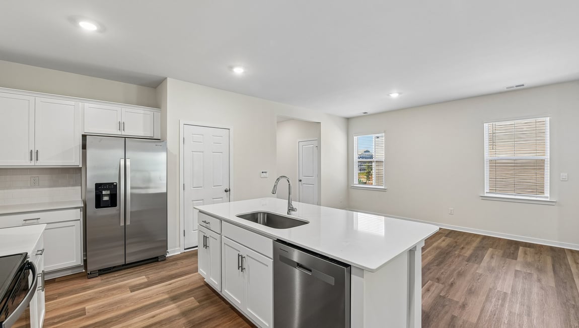 Kitchen and island with white cabinets and wood flooring