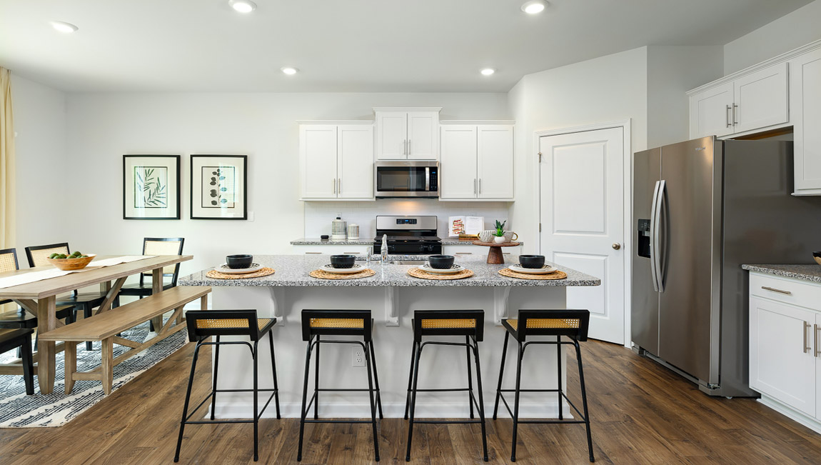 Kitchen and island with white cabinets and counters, and stainless steel appliances