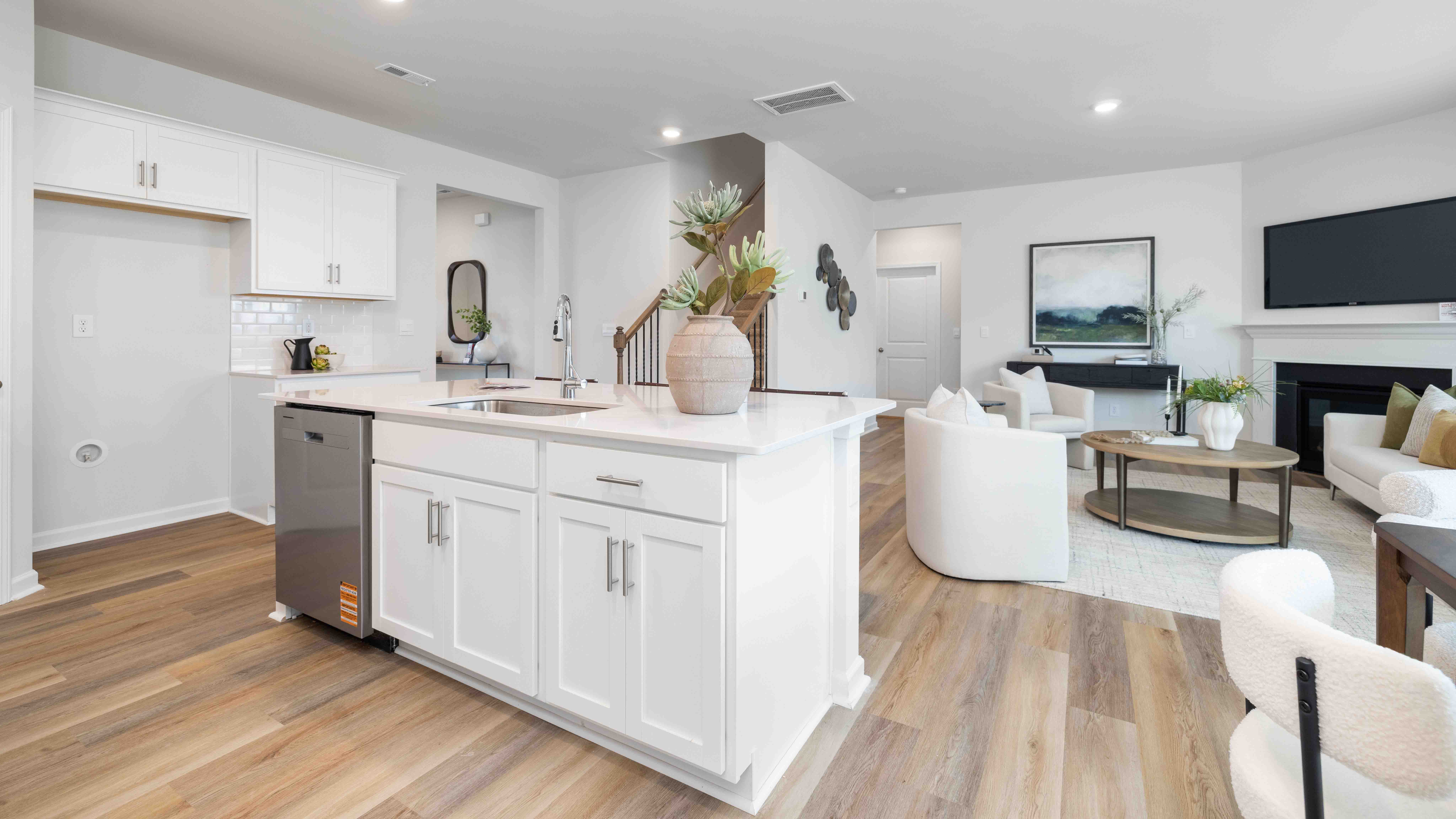 Kitchen and island with white cabinets and counters, and stainless steel appliances