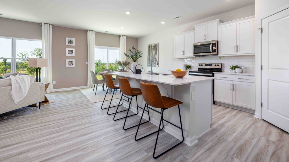 Kitchen and island with white cabinets and counters, and stainless steel appliances