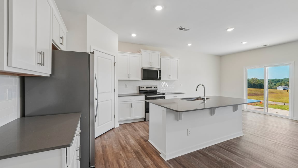 Kitchen and island with white cabinets and counters, and stainless steel appliances