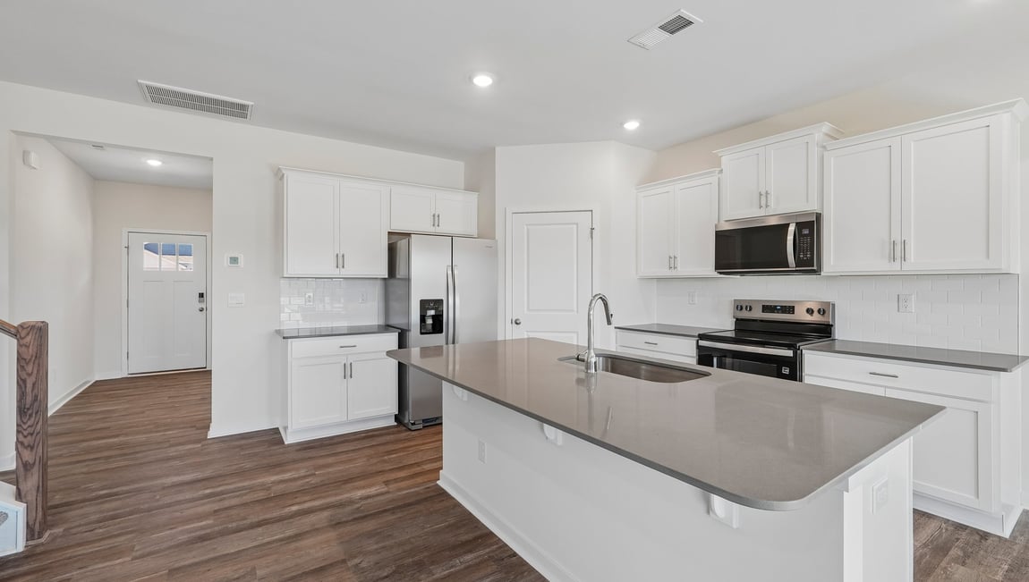 Kitchen and island with white cabinets and counters, and stainless steel appliances