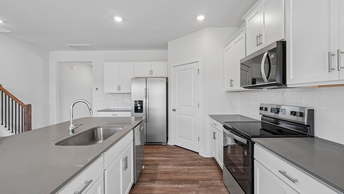 Kitchen and island with white cabinets and counters, and stainless steel appliances