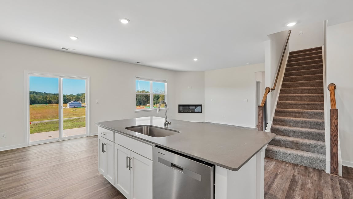 Kitchen and island with white cabinets and counters, and stainless steel appliances