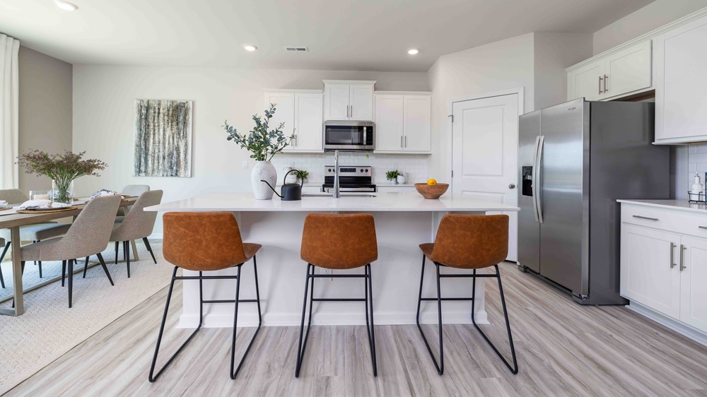 Kitchen and island with white cabinets and counters, and stainless steel appliances