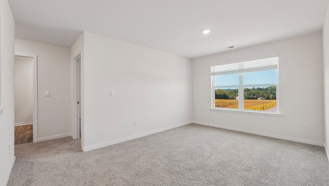 Carpeted loft area with windows