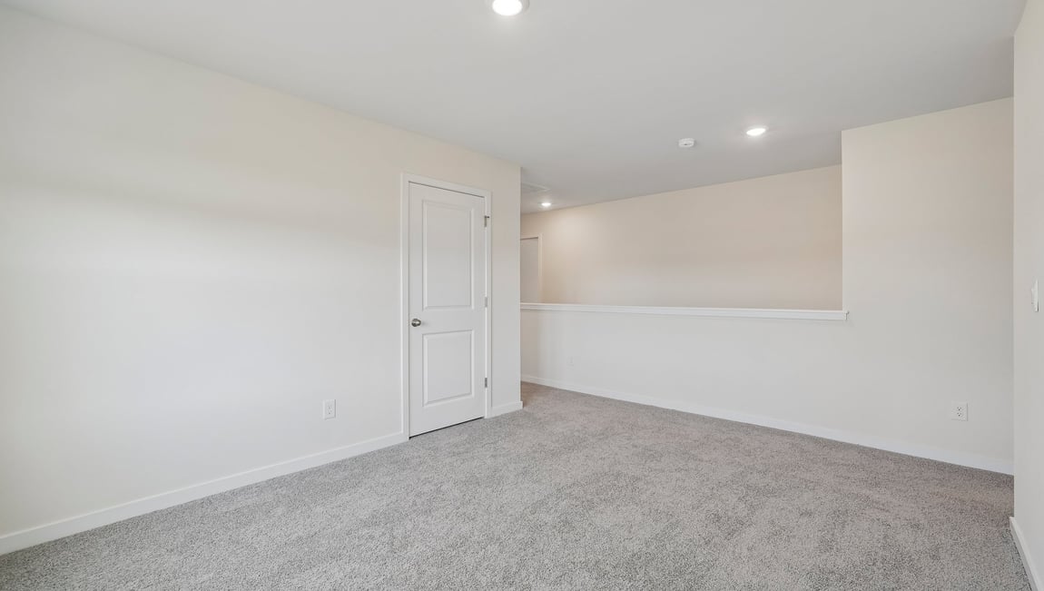 Carpeted loft area with windows