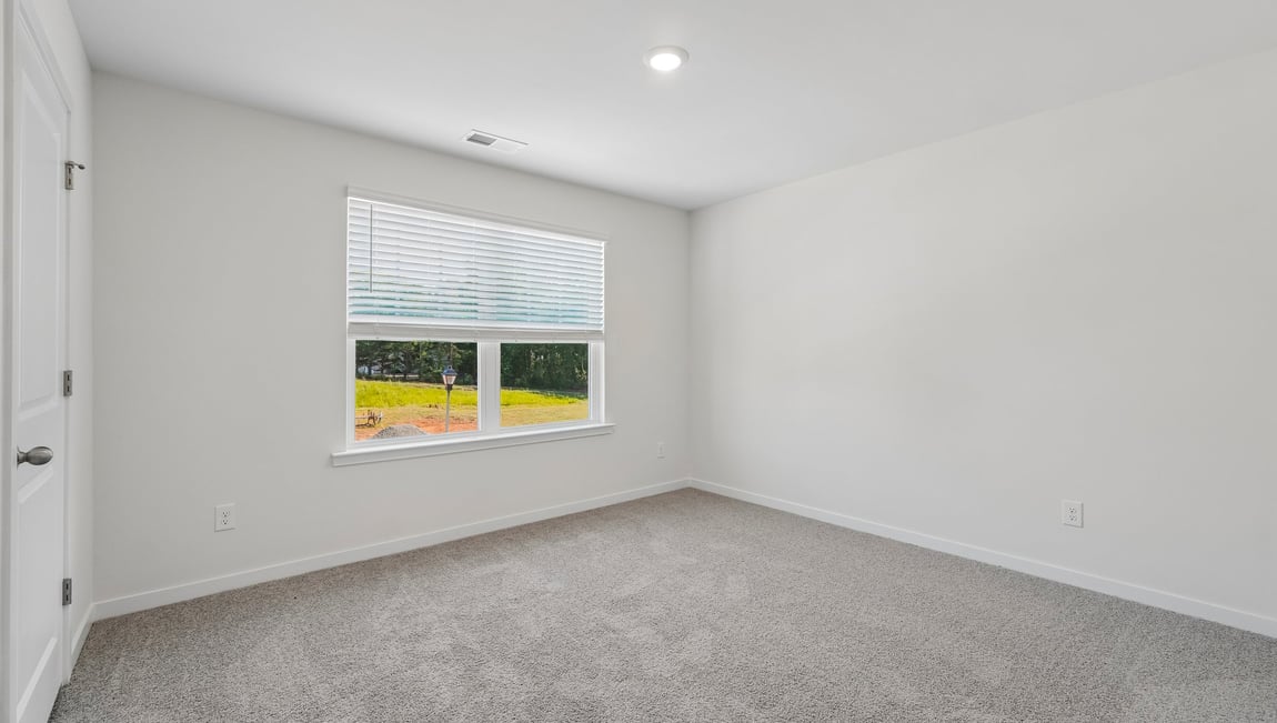 Carpeted loft area with windows