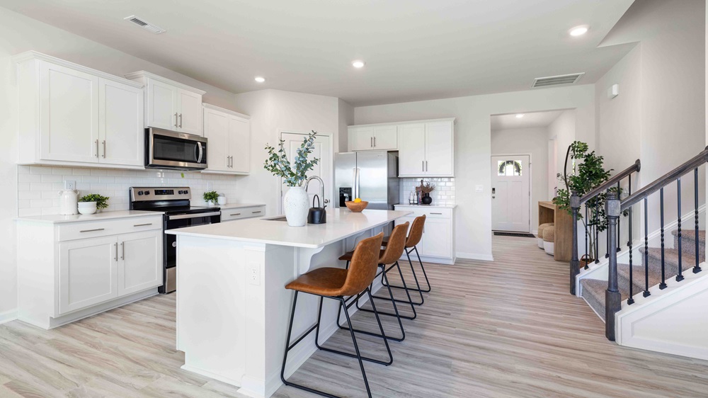 Kitchen and island with white cabinets and counters, and stainless steel appliances