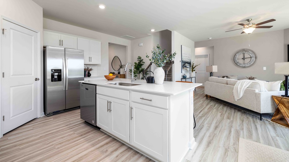 Kitchen and island with white cabinets and counters, and stainless steel appliances