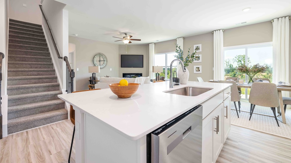 Kitchen and island with white cabinets and counters, and stainless steel appliances
