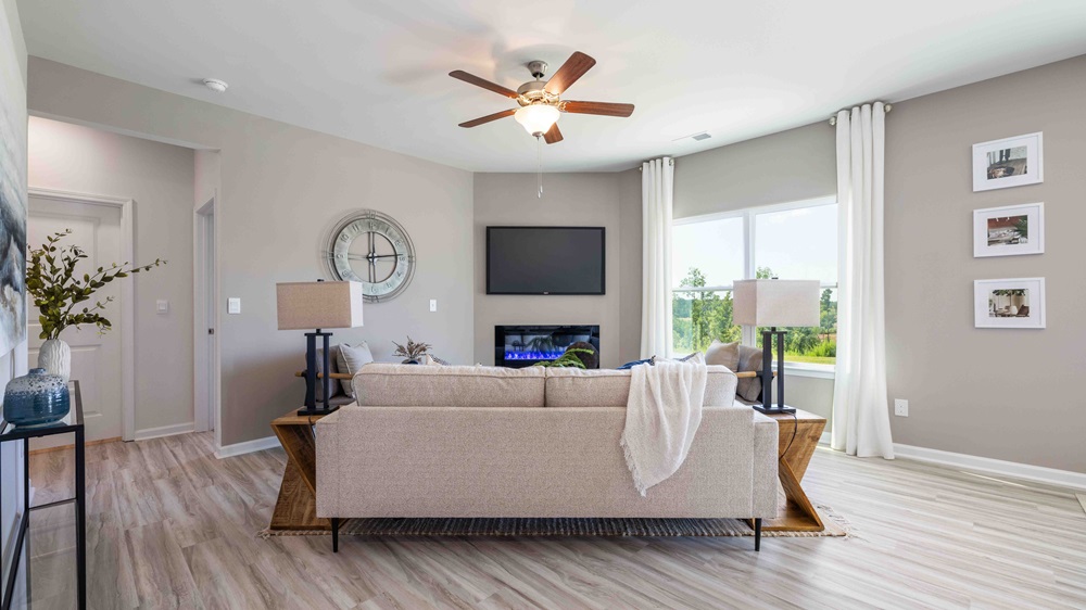 Living room beside kitchen with large window, and electric fireplace