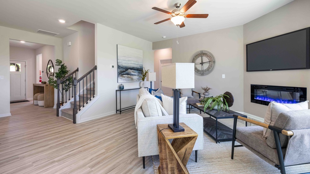 Living room beside kitchen with large window, and electric fireplace
