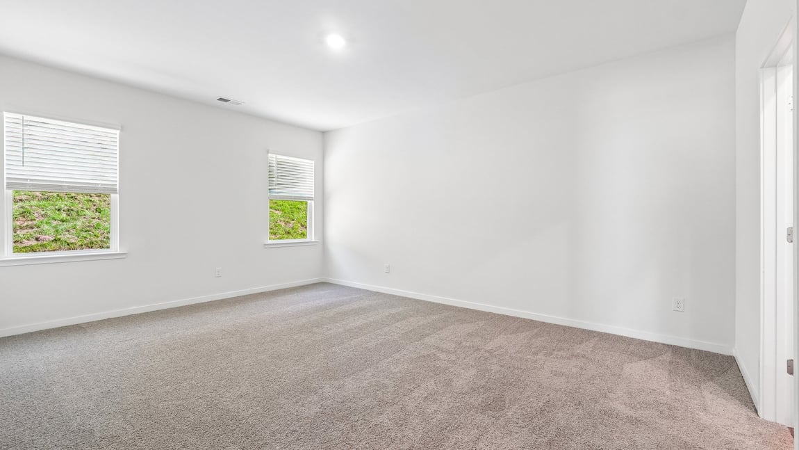 Primary carpeted bedroom with windows