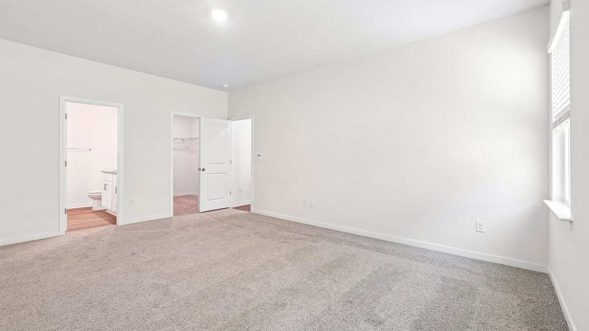 Primary carpeted bedroom with windows