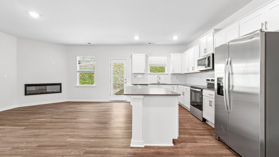 Kitchen and island with white cabinets and wood flooring