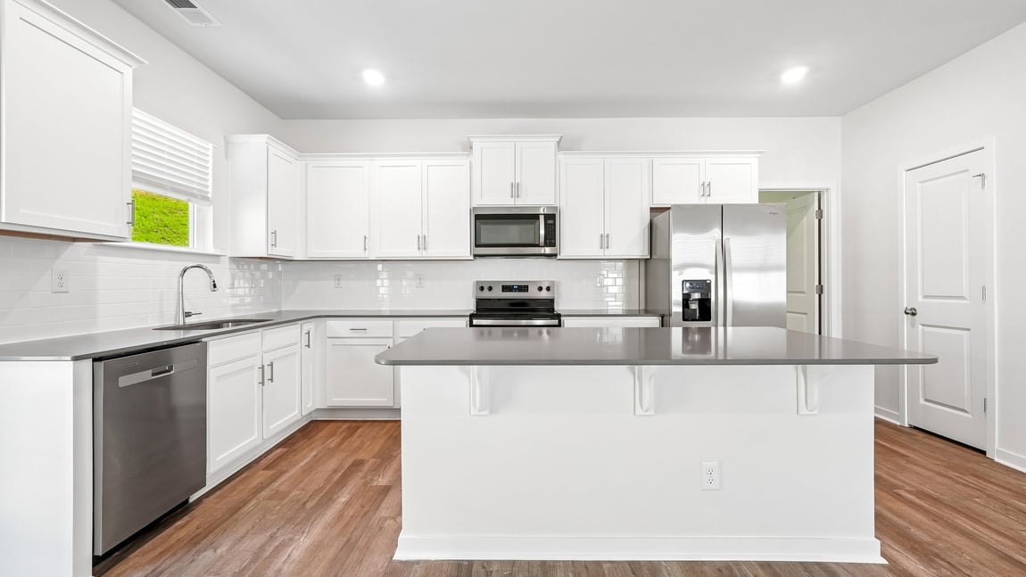 Kitchen and island with white cabinets and wood flooring