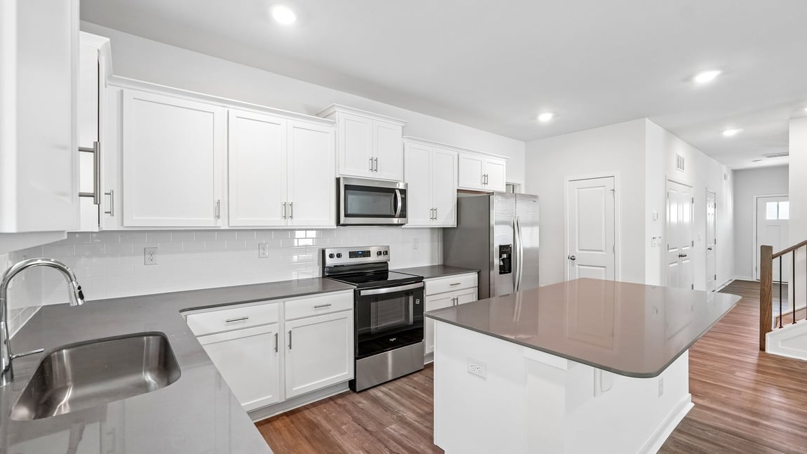 Kitchen and island with white cabinets and wood flooring
