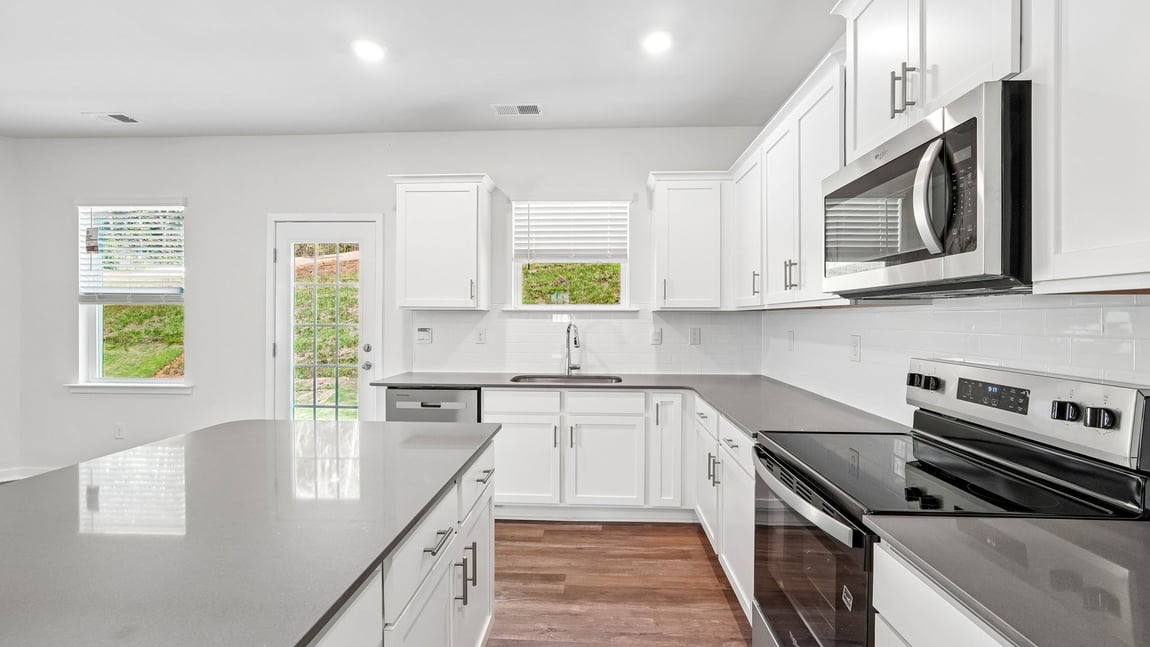 Kitchen and island with white cabinets and wood flooring